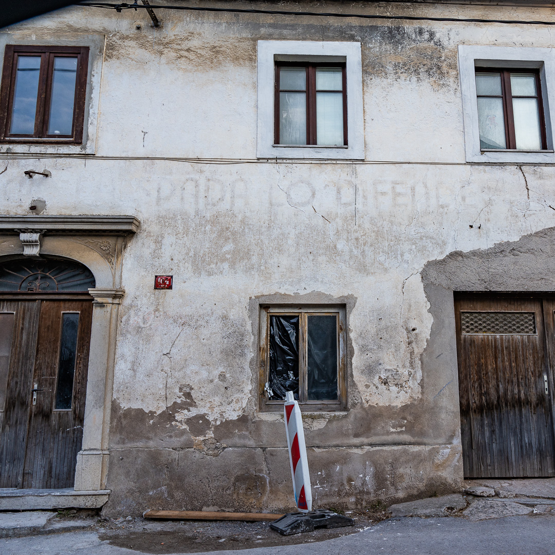 Ostanek fašistilnega reka na fasadi : "È l'aratro che traccia il solco, ma è la spada che lo difende" - Plug je tisti, ki zariše brazdo, a meč jo brani